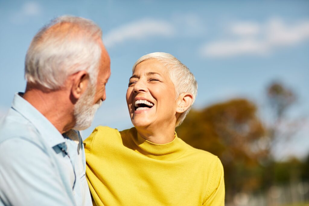 Woman in yellow sweater laughing outside with man in blue shirt